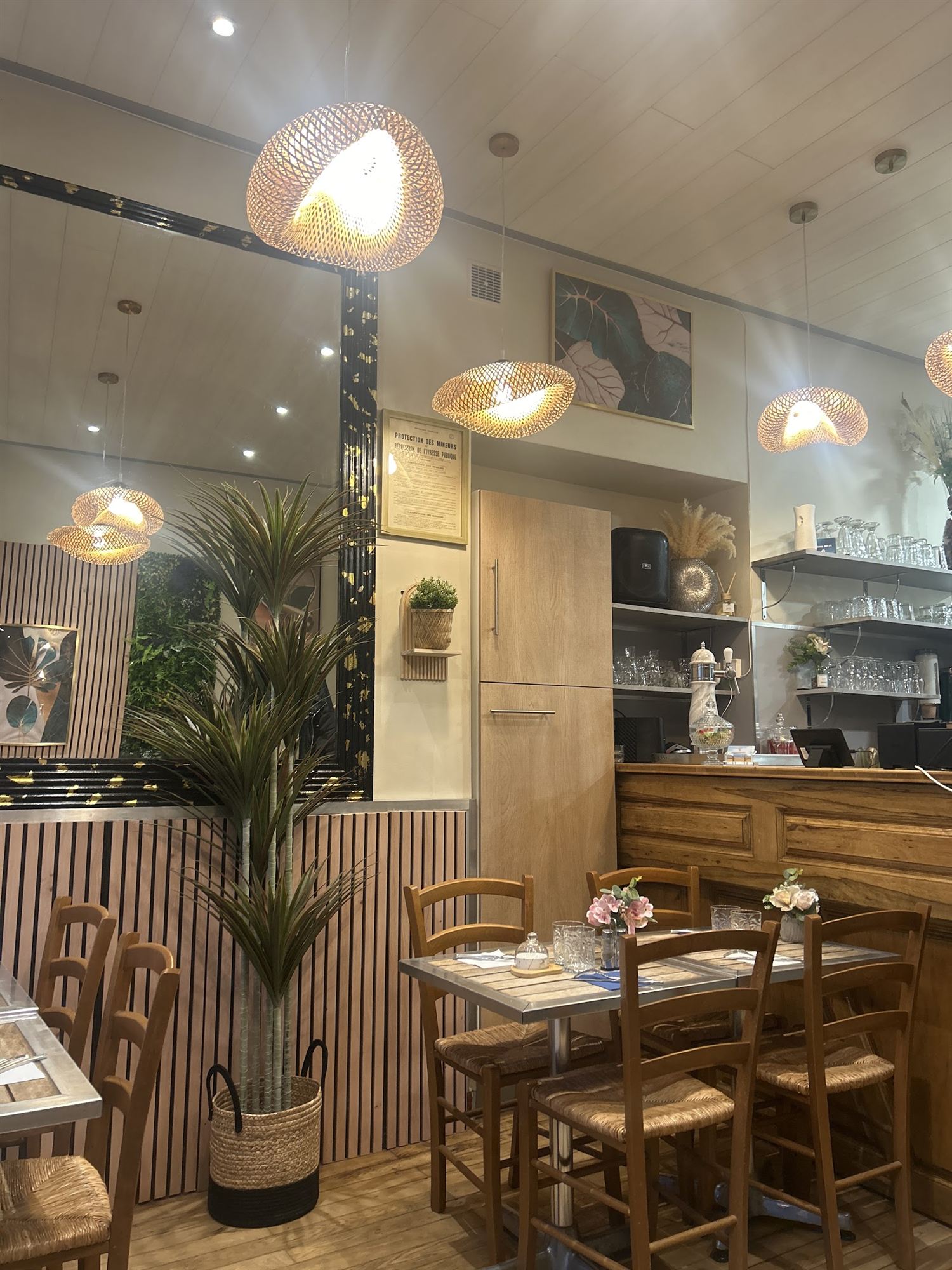 Salle du restaurant : suspensions en rotin, lambris bois et plantes