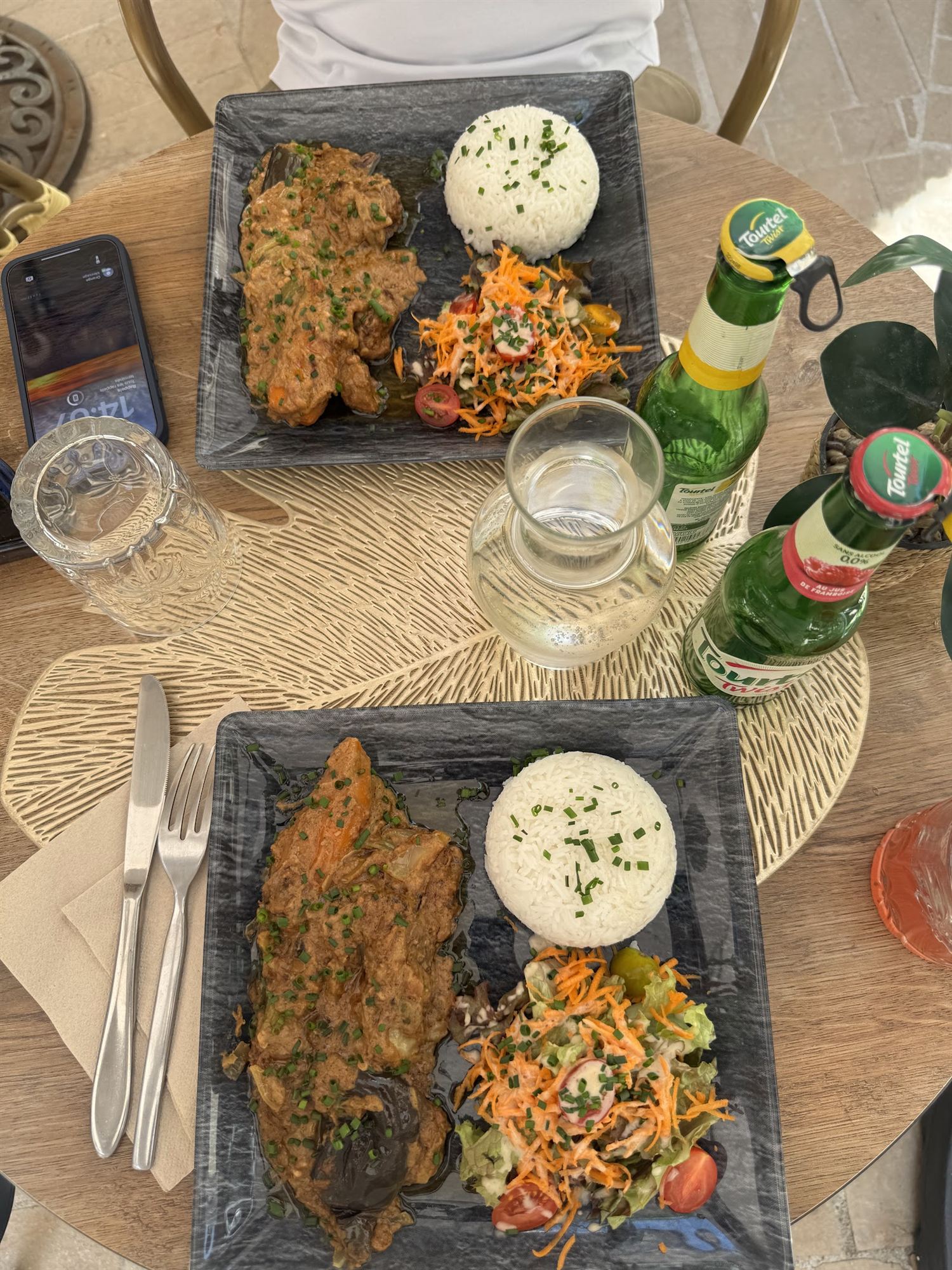 Deux assiettes de mafé de bœuf avec riz blanc et salade, servies en terrasse