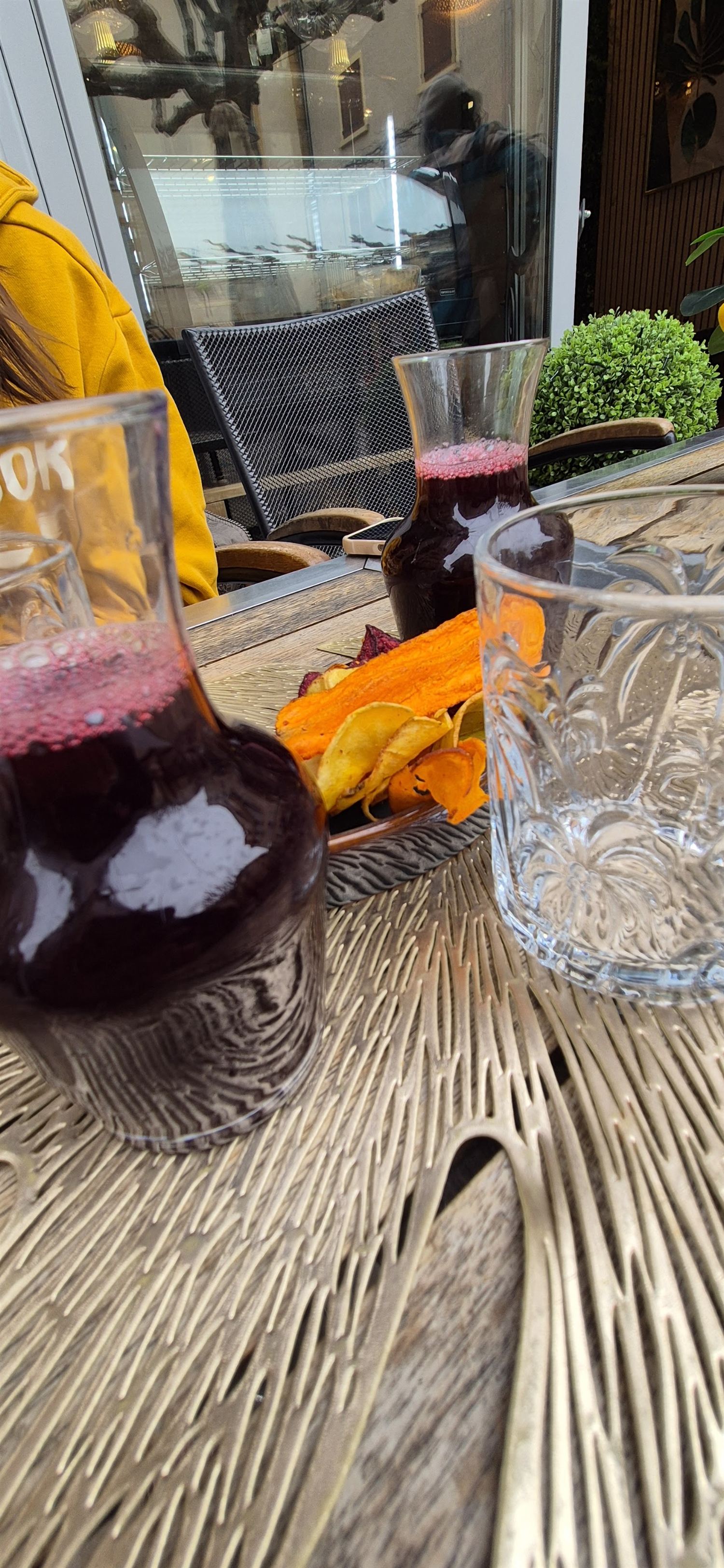 Deux carafes de bissap rouge profond posées sur une table, avec des chips de légumes