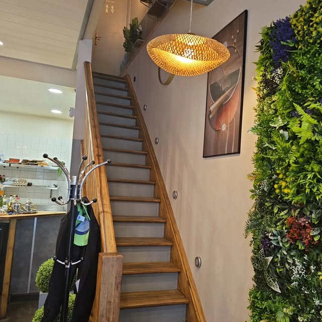 L'escalier en bois du restaurant, suspension en rotin et mur de verdure