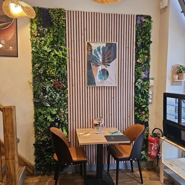 Table pour deux devant un mur végétal et un panneau en lames de bois