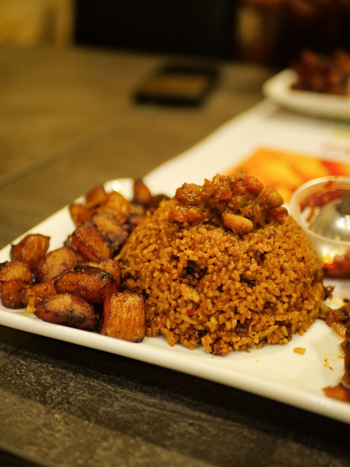 Alloco, banane plantain frite, et riz jollof dans une assiette
