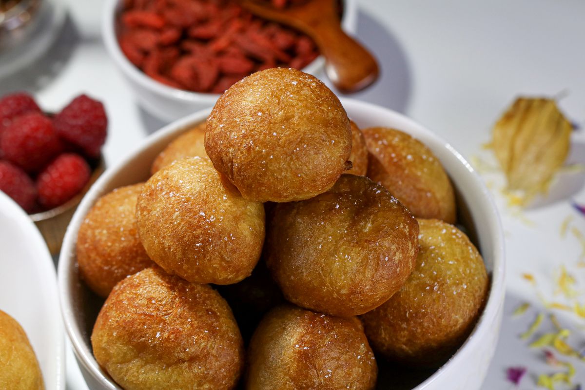 Beignets dorés saupoudrés de sucre, empilés dans un bol blanc