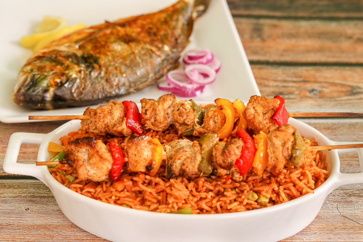 Riz rouge parfumé servi avec des brochettes de poulet et un poisson entier grillé
